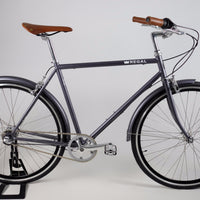 Commuter Bike with a three speed internal hub, made with a steel frame, matte gray in colour, and black rims.