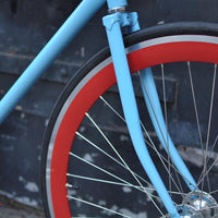 This fixed gear bicycle is called "The Maquis" and features red rims and a sky blue frame.