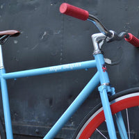 This fixed gear bicycle is called "The Maquis" and features red rims and a sky blue frame.