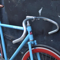 This fixed gear bicycle is called "The Maquis" and features red rims and a sky blue frame.