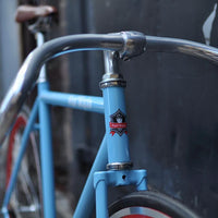 This fixed gear bicycle is called "The Maquis" and features red rims and a sky blue frame.