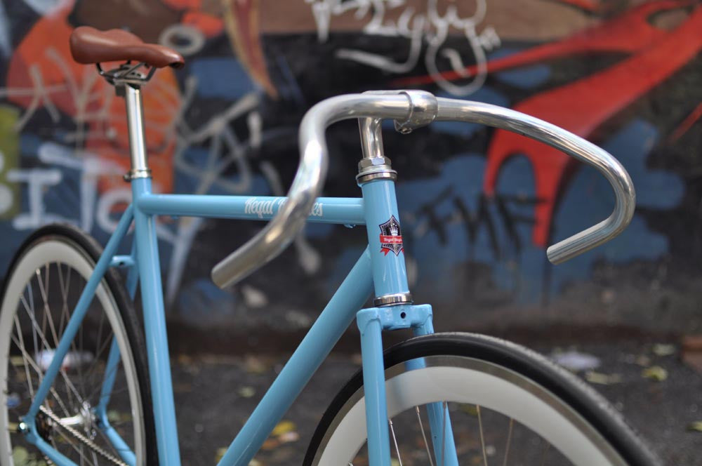 This fixed gear bicycle is called "The Prince" and features white rims and a sky blue frame.