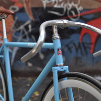 This fixed gear bicycle is called "The Prince" and features white rims and a sky blue frame.