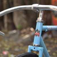 This fixed gear bicycle is called "The Prince" and features white rims and a sky blue frame.