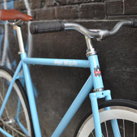 This fixed gear bicycle is called "The Prince" and features white rims and a sky blue frame.