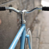 This fixed gear bicycle is called "The Prince" and features white rims and a sky blue frame.