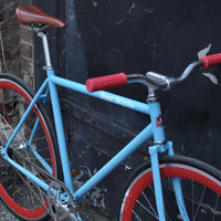 This fixed gear bicycle is called "The Maquis" and features red rims and a sky blue frame.