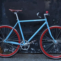 This fixed gear bicycle is called "The Maquis" and features red rims and a sky blue frame.