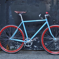 This fixed gear bicycle is called "The Maquis" and features red rims and a sky blue frame.