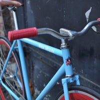 This fixed gear bicycle is called "The Maquis" and features red rims and a sky blue frame.