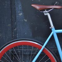 This fixed gear bicycle is called "The Maquis" and features red rims and a sky blue frame.