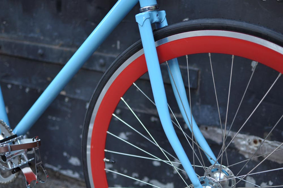 This fixed gear bicycle is called "The Maquis" and features red rims and a sky blue frame.