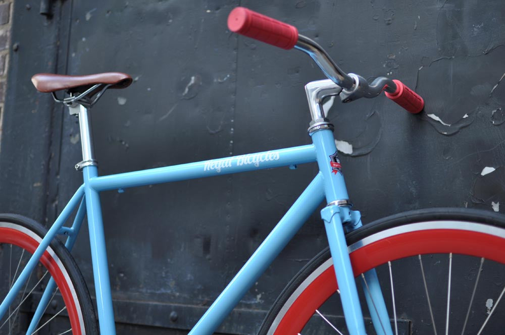 This fixed gear bicycle is called "The Maquis" and features red rims and a sky blue frame.