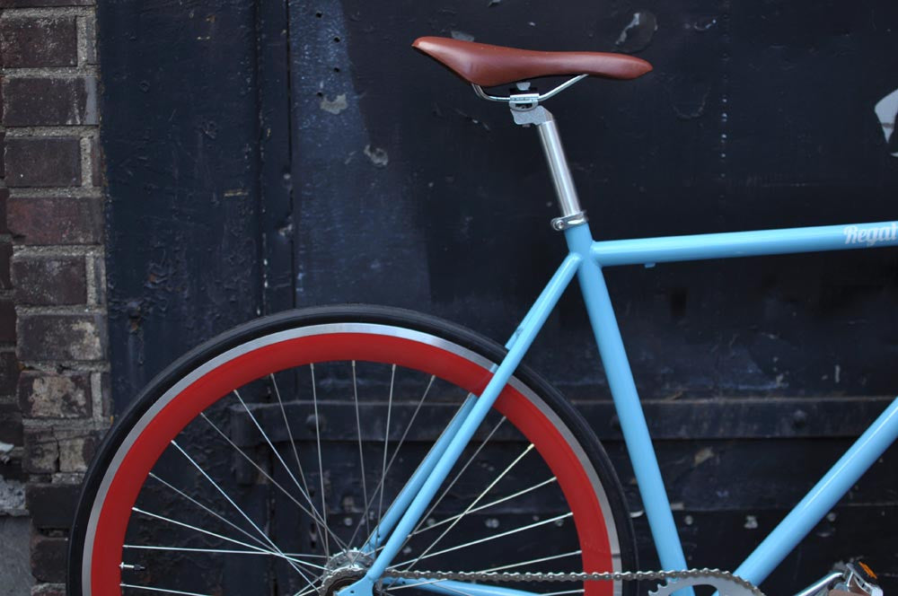 This fixed gear bicycle is called "The Maquis" and features red rims and a sky blue frame.