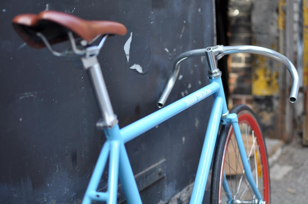 This fixed gear bicycle is called "The Maquis" and features red rims and a sky blue frame.