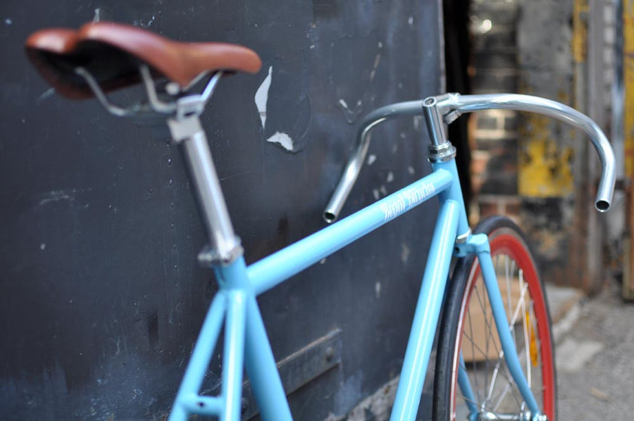 This fixed gear bicycle is called "The Maquis" and features red rims and a sky blue frame.