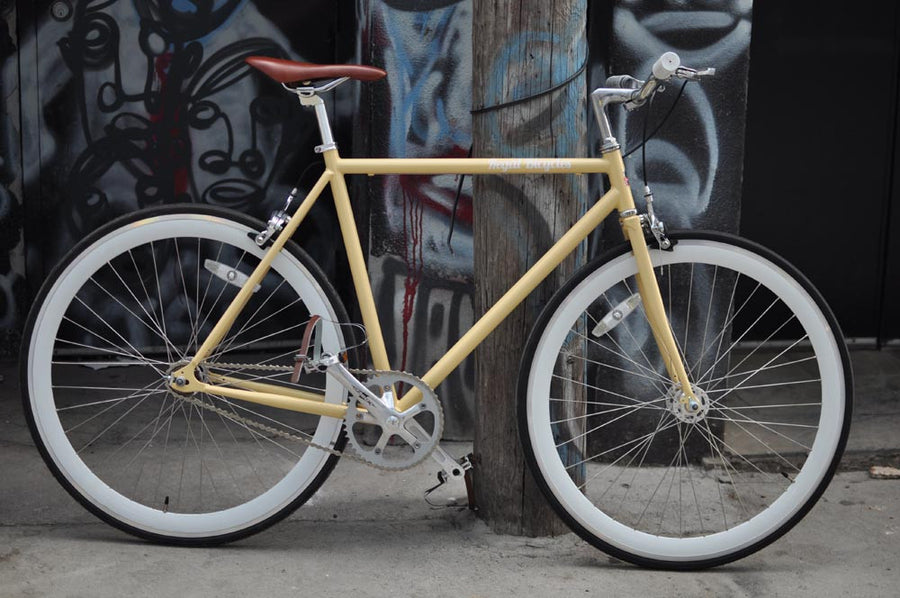 This fixed gear bicycle is called "The Count" and features white rims and a cream frame.