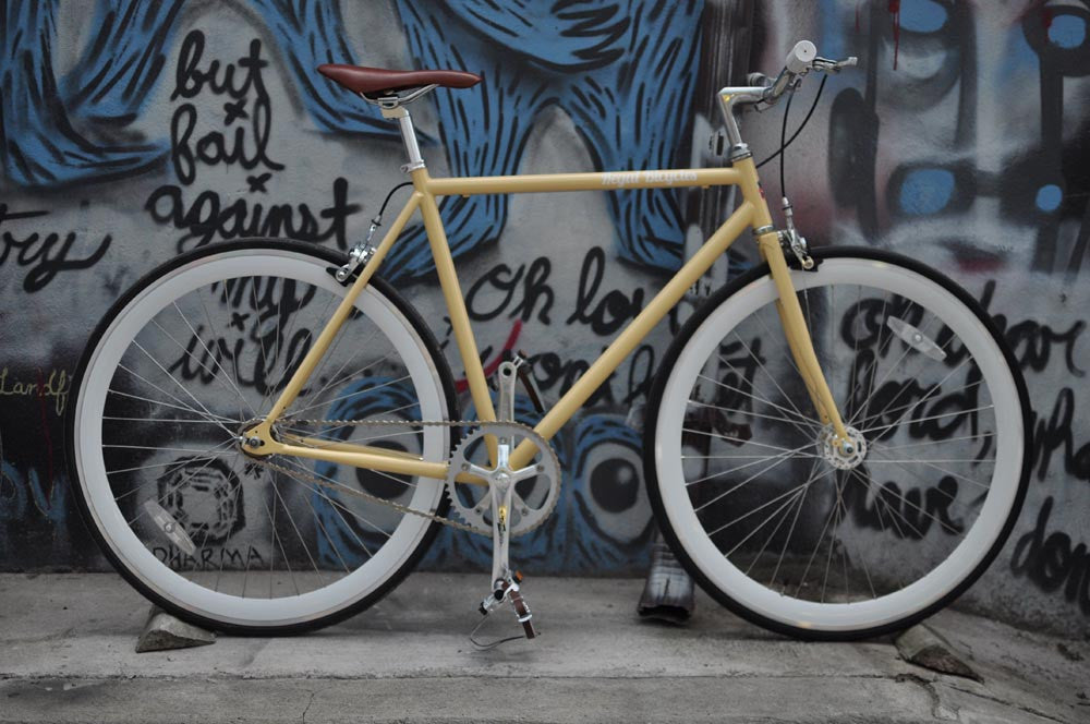 This fixed gear bicycle is called "The Count" and features white rims and a cream frame.