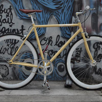 This fixed gear bicycle is called "The Count" and features white rims and a cream frame.