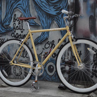 This fixed gear bicycle is called "The Count" and features white rims and a cream frame.