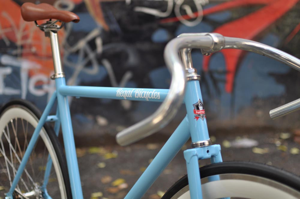 This fixed gear bicycle is called "The Prince" and features white rims and a sky blue frame.