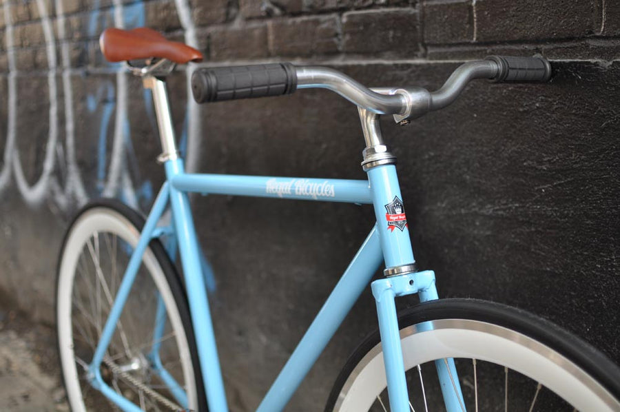 This fixed gear bicycle is called "The Prince" and features white rims and a sky blue frame.