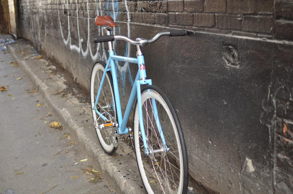 This fixed gear bicycle is called "The Prince" and features white rims and a sky blue frame.