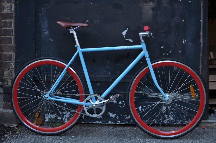 This fixed gear bicycle is called "The Maquis" and features red rims and a sky blue frame.