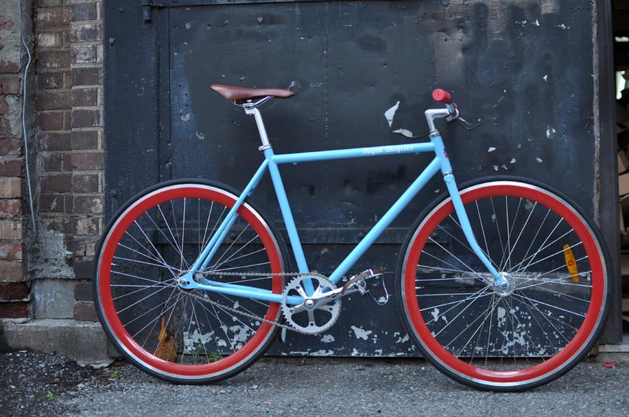 This fixed gear bicycle is called "The Maquis" and features red rims and a sky blue frame.