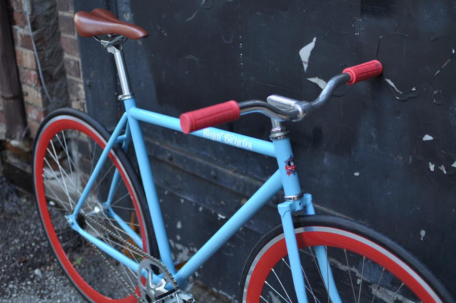 This fixed gear bicycle is called "The Maquis" and features red rims and a sky blue frame.