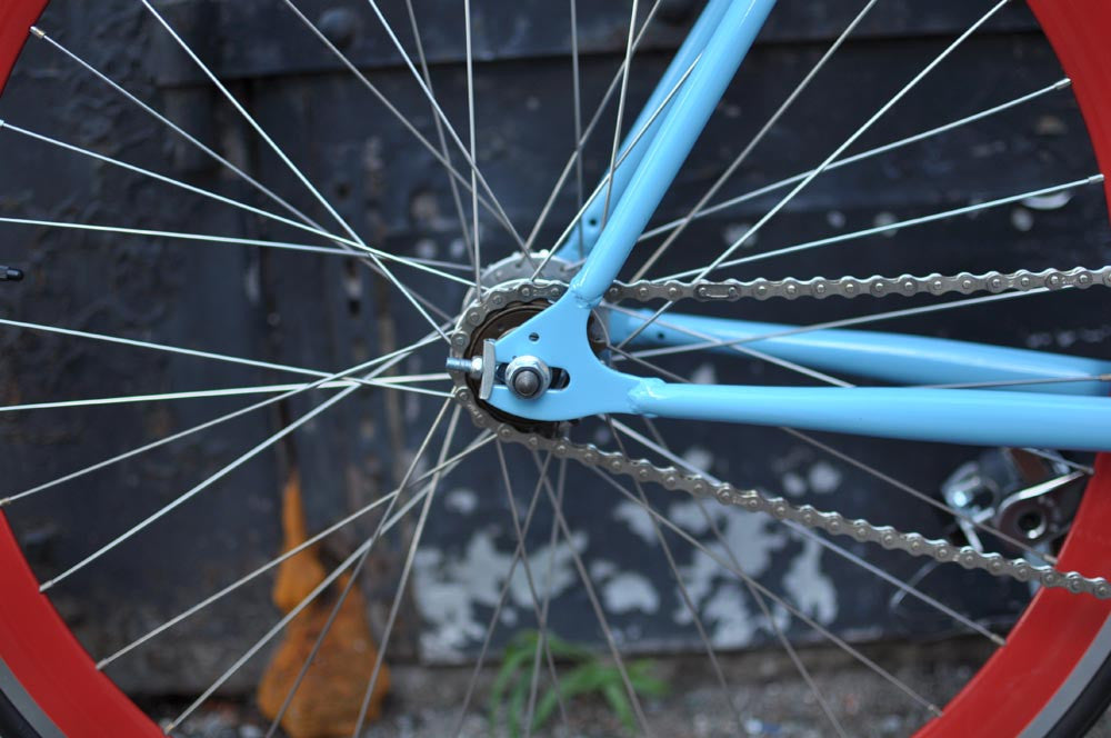 This fixed gear bicycle is called "The Maquis" and features red rims and a sky blue frame.